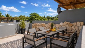 En udendørs patio med et spisebord, omgivet af stenvægge og en træpergola.