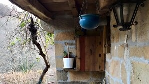 A rustic wooden table with a bench, a hanging blue pot, a potted plant, and a wall-mounted lantern. - Lo Macario Pasiego Cabin (Resconorio)