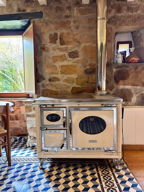 A stone wall, a vintage stove, and a patterned floor.