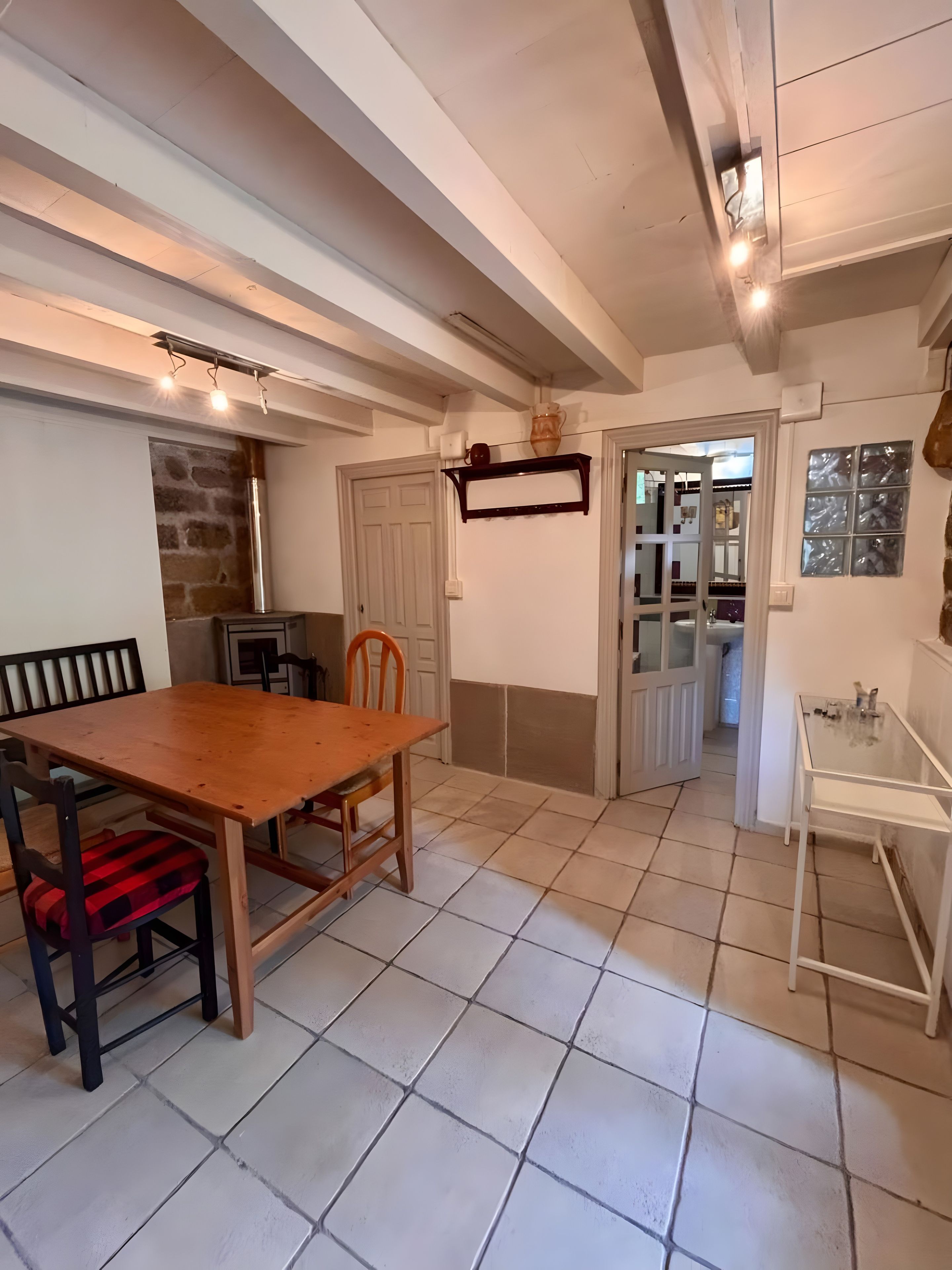 Un coin repas avec une table et des chaises en bois, un mur en pierre et une porte donnant sur une autre pièce.
