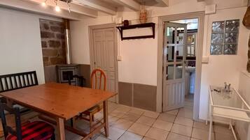 Un coin repas avec une table et des chaises en bois, un mur en pierre et une porte donnant sur une autre pièce.