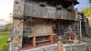 A rustic stone building with a wooden bench and a small table outside. - Lo Macario Pasiego Cabin (Resconorio)