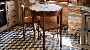 A stone-walled kitchen with a round table, chairs, and a window with a view of trees. - Lo Macario Pasiego Cabin (Resconorio)