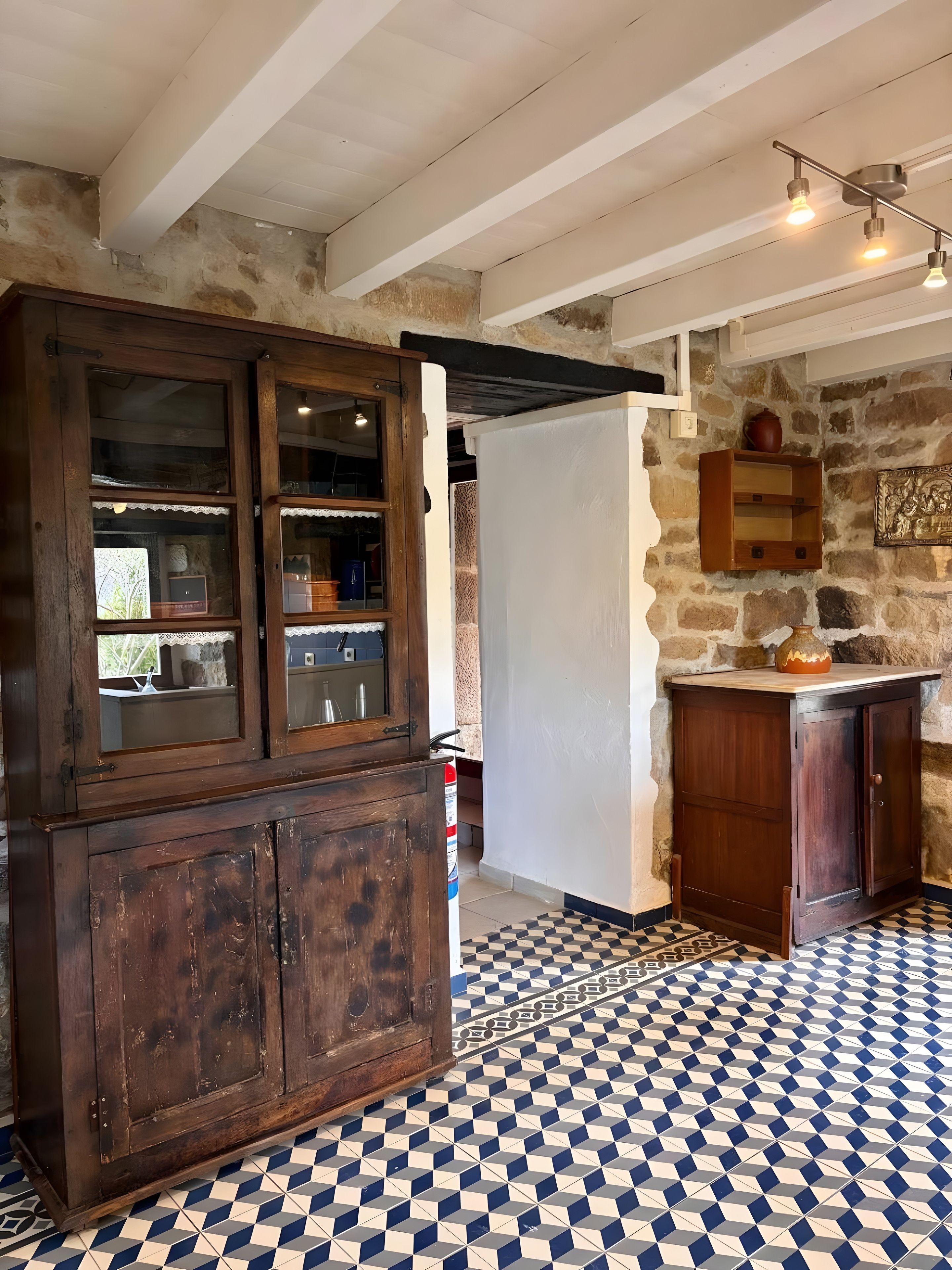 Una cocina rústica con piso de cuadros, armarios de madera y pared de piedra.