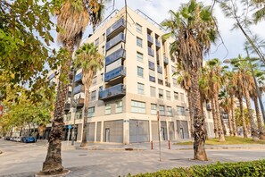 Un edificio residencial de varios pisos con balcones, rodeado de palmeras y un cielo despejado.
