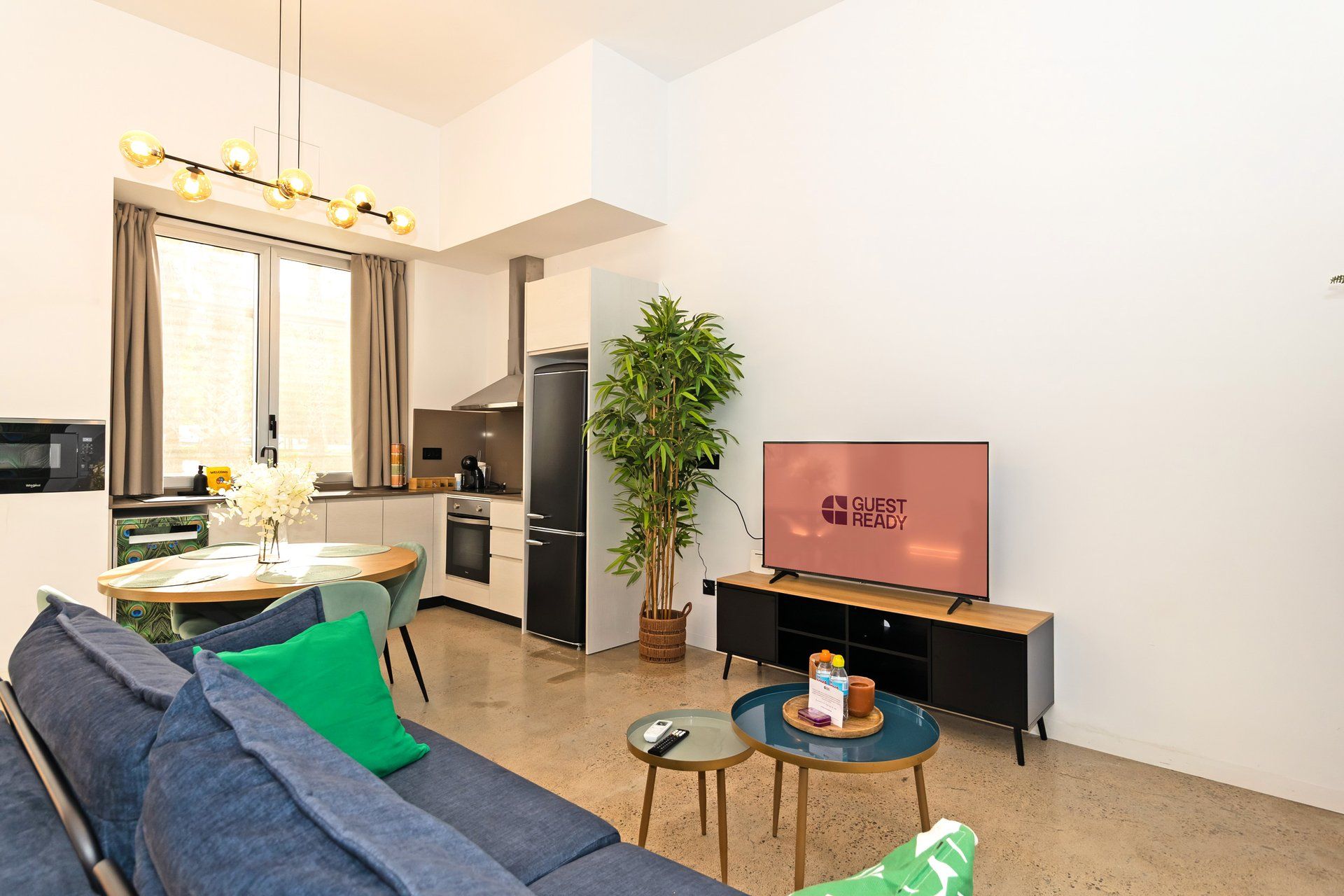Un espacio habitable compacto con sofá, una mesa de comedor, televisor y zona de cocina.