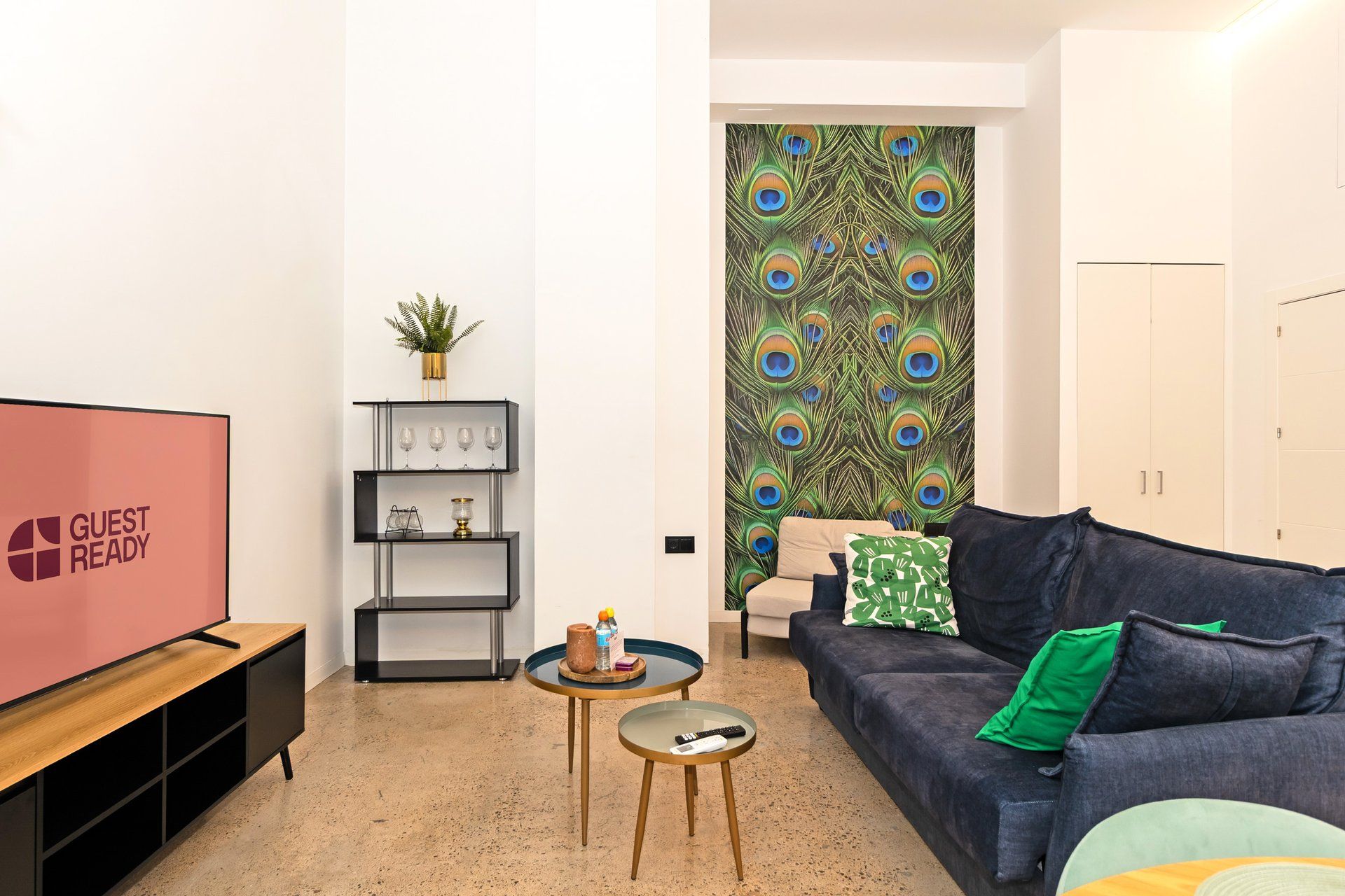 Una sala de estar moderna con una televisión de pantalla plana, un sofá, una mesa de centro y una estantería.