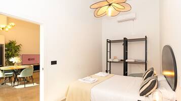 Una habitación de hotel con cama, mesita de noche y zona de escritorio con sillas.