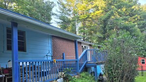 Une maison bleue avec une partie en briques, un escalier bleu et un jardin.