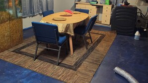 Une pièce comprenant une table à manger, des chaises, un ventilateur de plafond et un tapis.