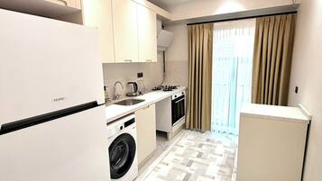 A compact kitchen with a washing machine, a sink, and a stove.