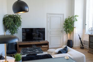 Un soggiorno moderno con una TV a schermo piatto, un tavolino in legno, un divano e una pianta in vaso.
