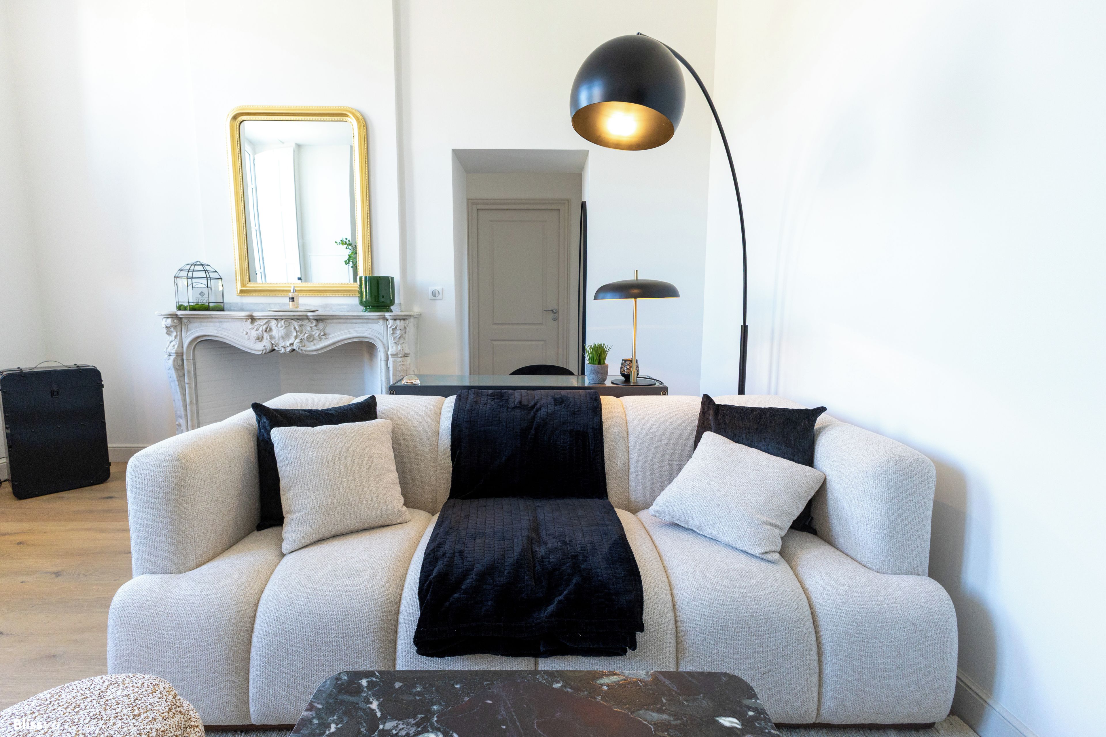 En stue med sofa, sofabord, lampe, pejs og spejl.