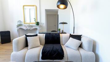 Una sala de estar con sofá, mesa de centro, lámpara, chimenea y espejo.