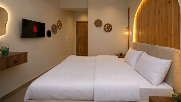 A hotel room with a bed, a TV mounted on the wall, and a wooden headboard. - Pyramids Height Luxury Wing (Giza Governorate)