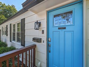 A house with a blue front door, a mailbox, and a window with shutters.
