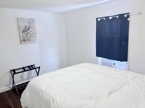 A bedroom with a bed, a window with a curtain, a wall-mounted shelf, and a painting. - Cozy Retreat - Nature Views - 5 Min to Sewanee (Sewanee)