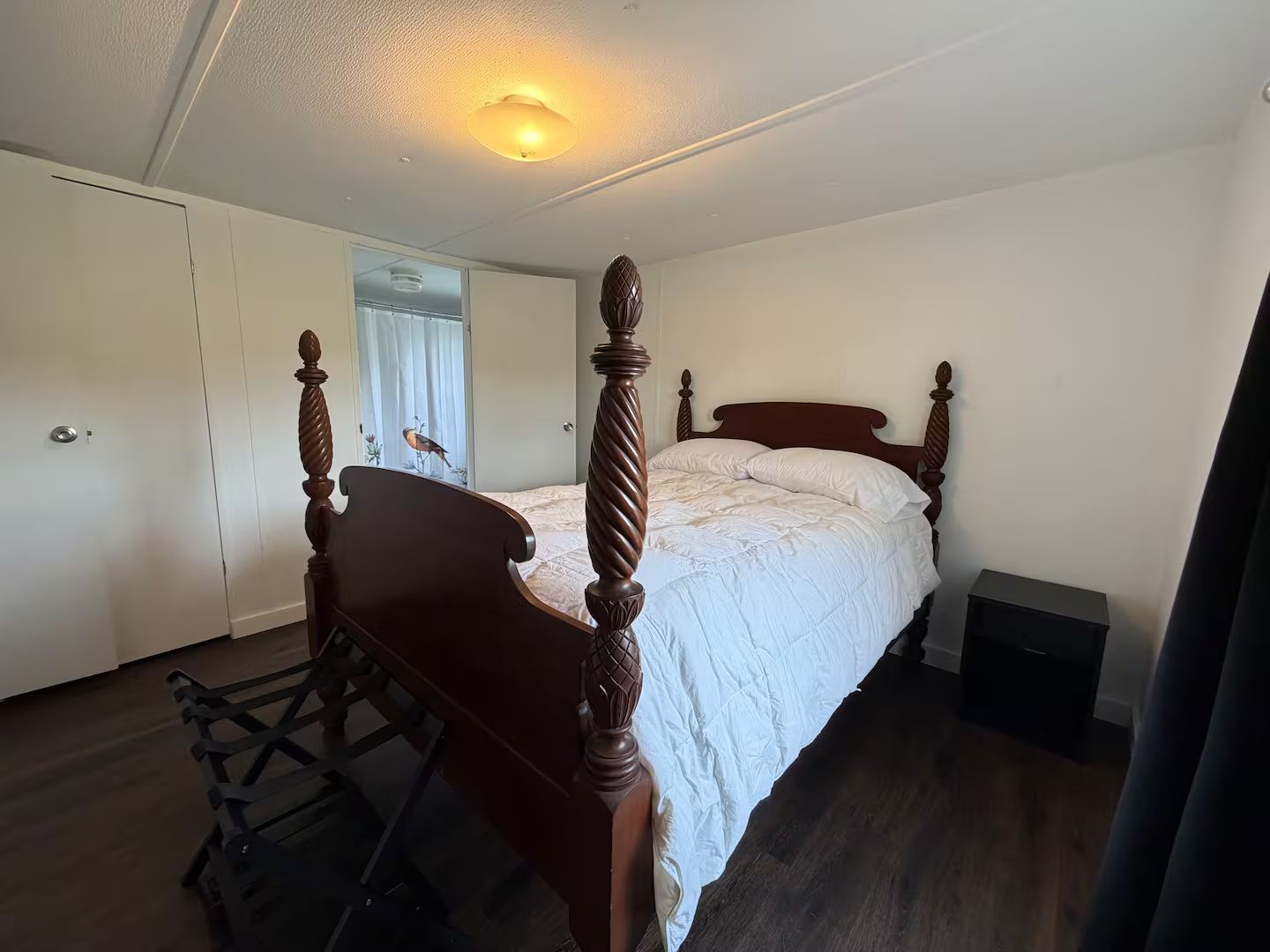 Une chambre à coucher avec un lit à baldaquin, une armoire et une petite table de chevet.