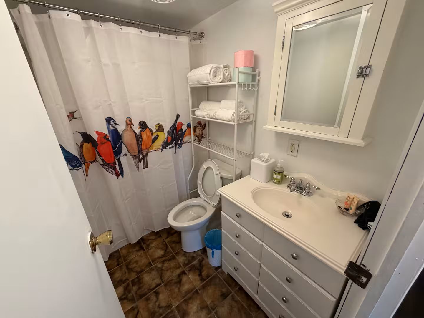 Un baño con inodoro, lavabo y toallero con toallas.