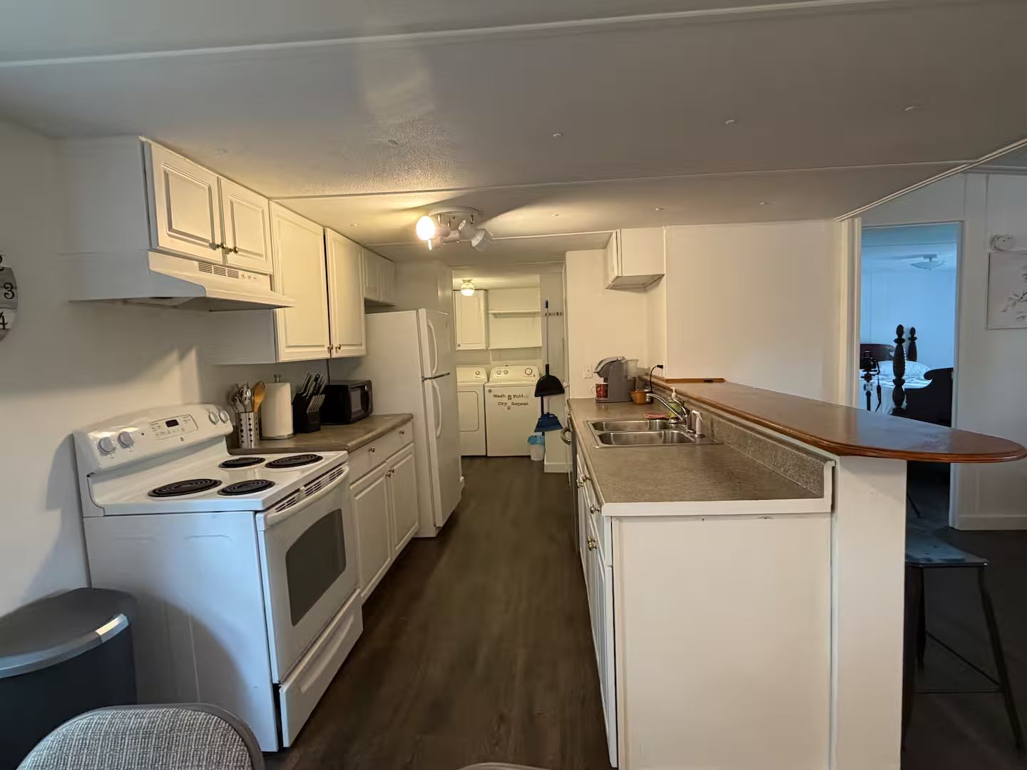 A compact kitchen with white cabinets, a stove, a refrigerator, and a sink.