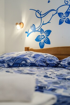 Ein Schlafzimmer mit einem Bett, einer Wandleuchte und einer Blumensticker.