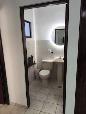 Baño pequeño y limpio con inodoro, lavabo y espejo.