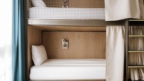 A bunk bed with a single bed below, a small shelf with a power outlet, and a curtain on the right side. - Glint Bordeaux (Bordeaux)