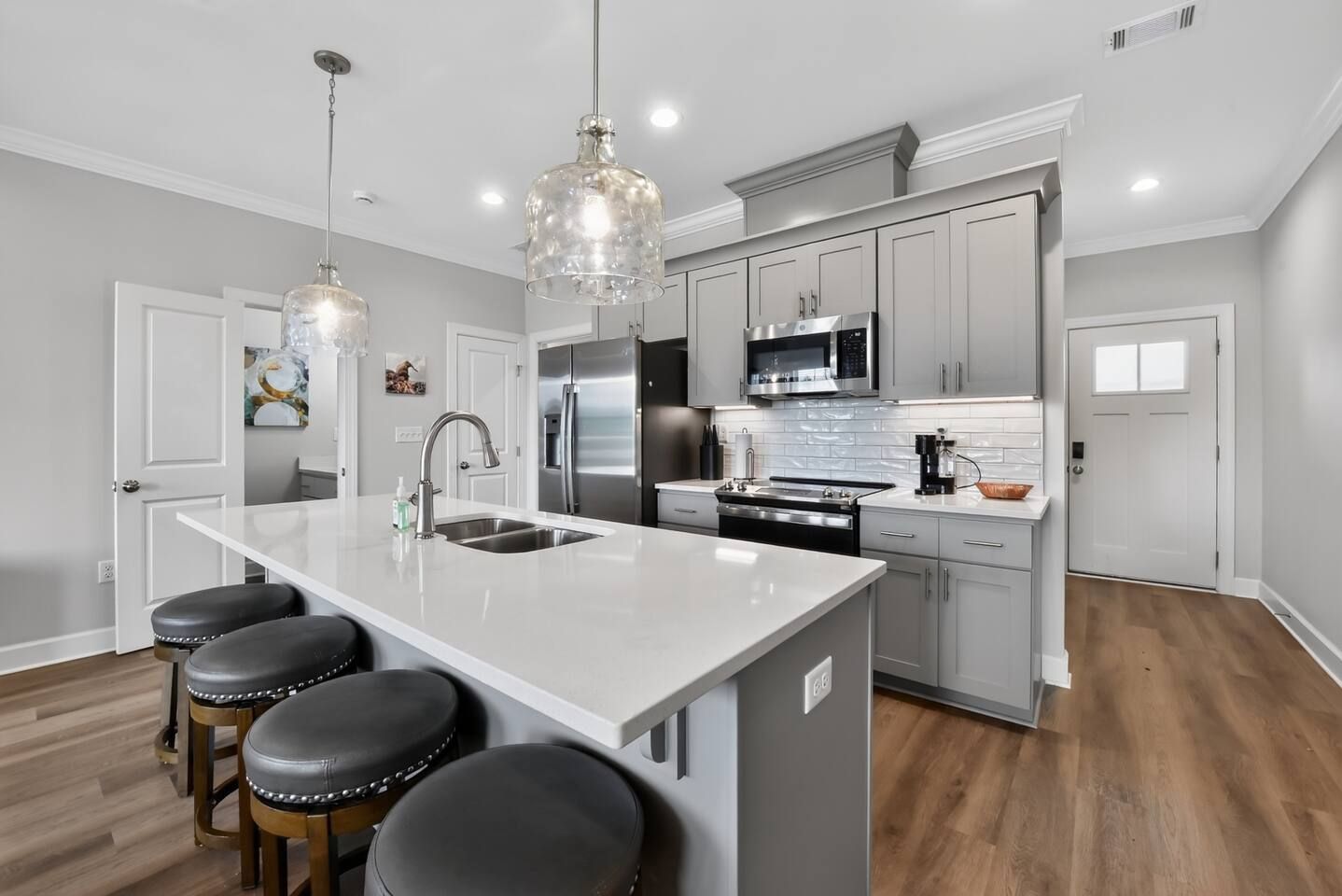 A modern kitchen with a central island, stainless steel appliances, and pendant lighting.