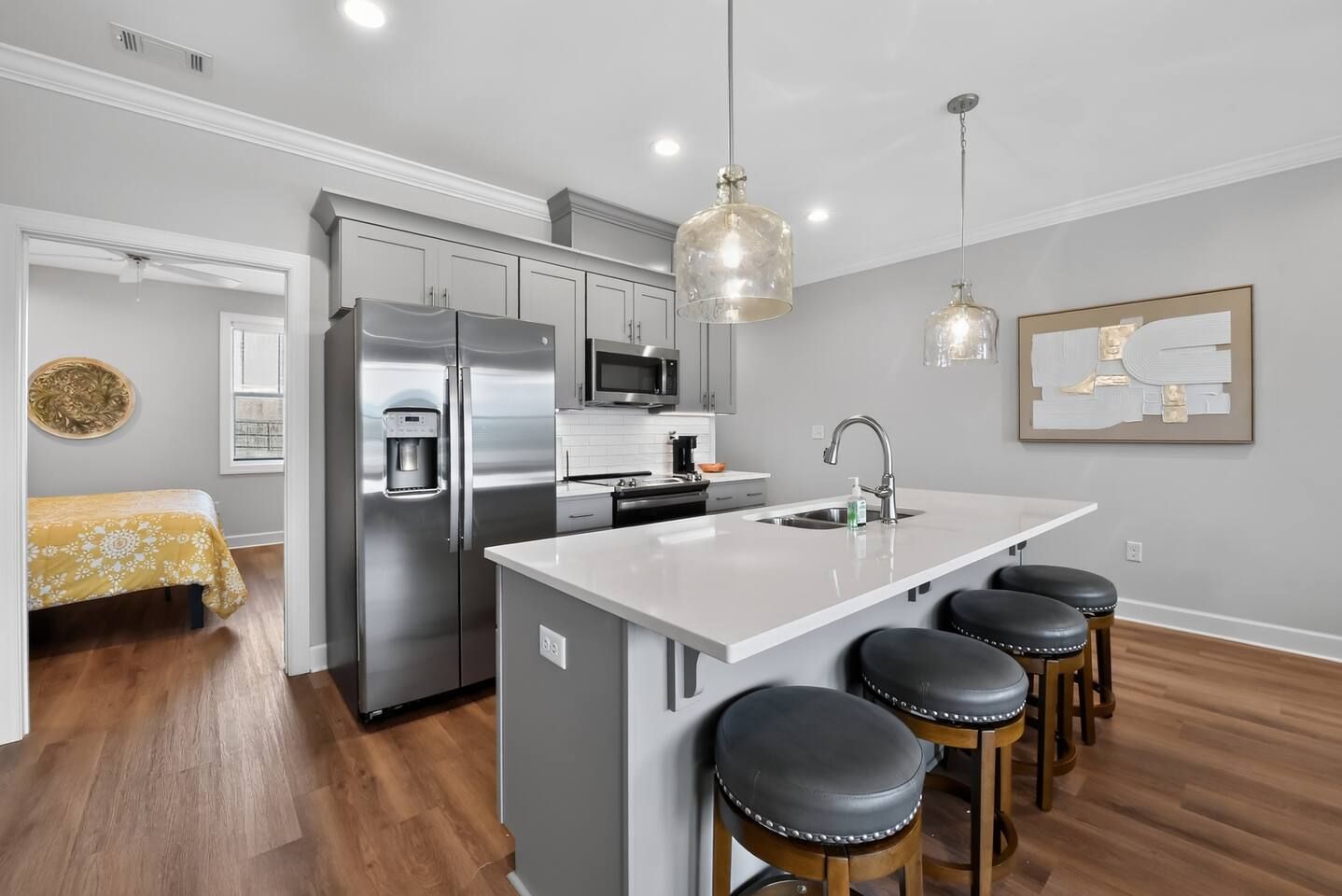 A modern kitchen with stainless steel appliances, a central island with stools, and pendant lighting.