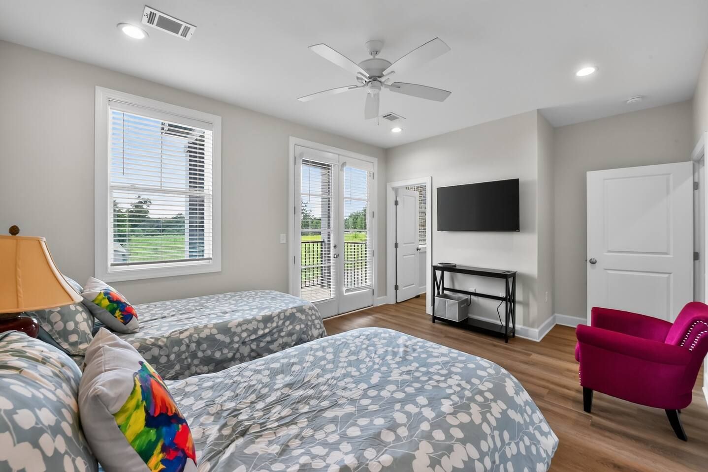 A bedroom with two beds, a TV, a desk, and a chair.