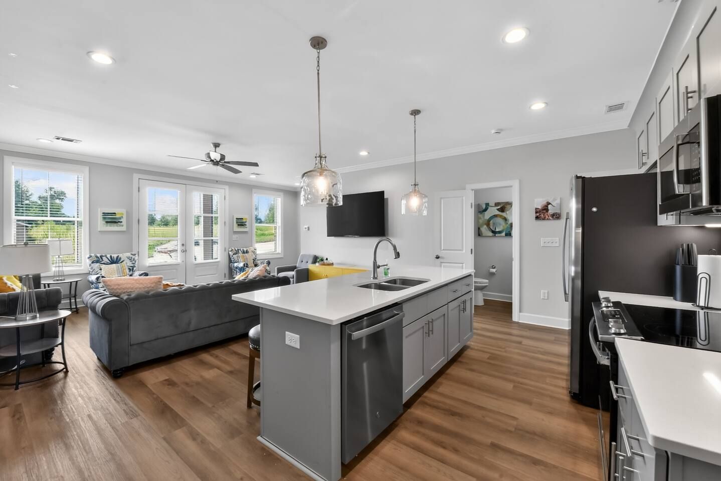 Una cocina moderna con una isla central, electrodomésticos integrados y un área de comedor con sofá y mesa.