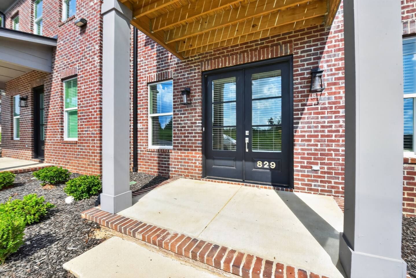A brick building with a black door, a visible address number, and a small front garden.