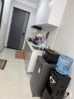 Eine kompakte Küche mit Kühlschrank, Mikrowelle, Spüle und Wasserspender.