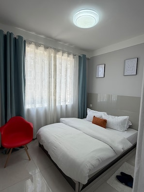Ein Hotelzimmer mit einem Bett, einem roten Sessel und Vorhängen.