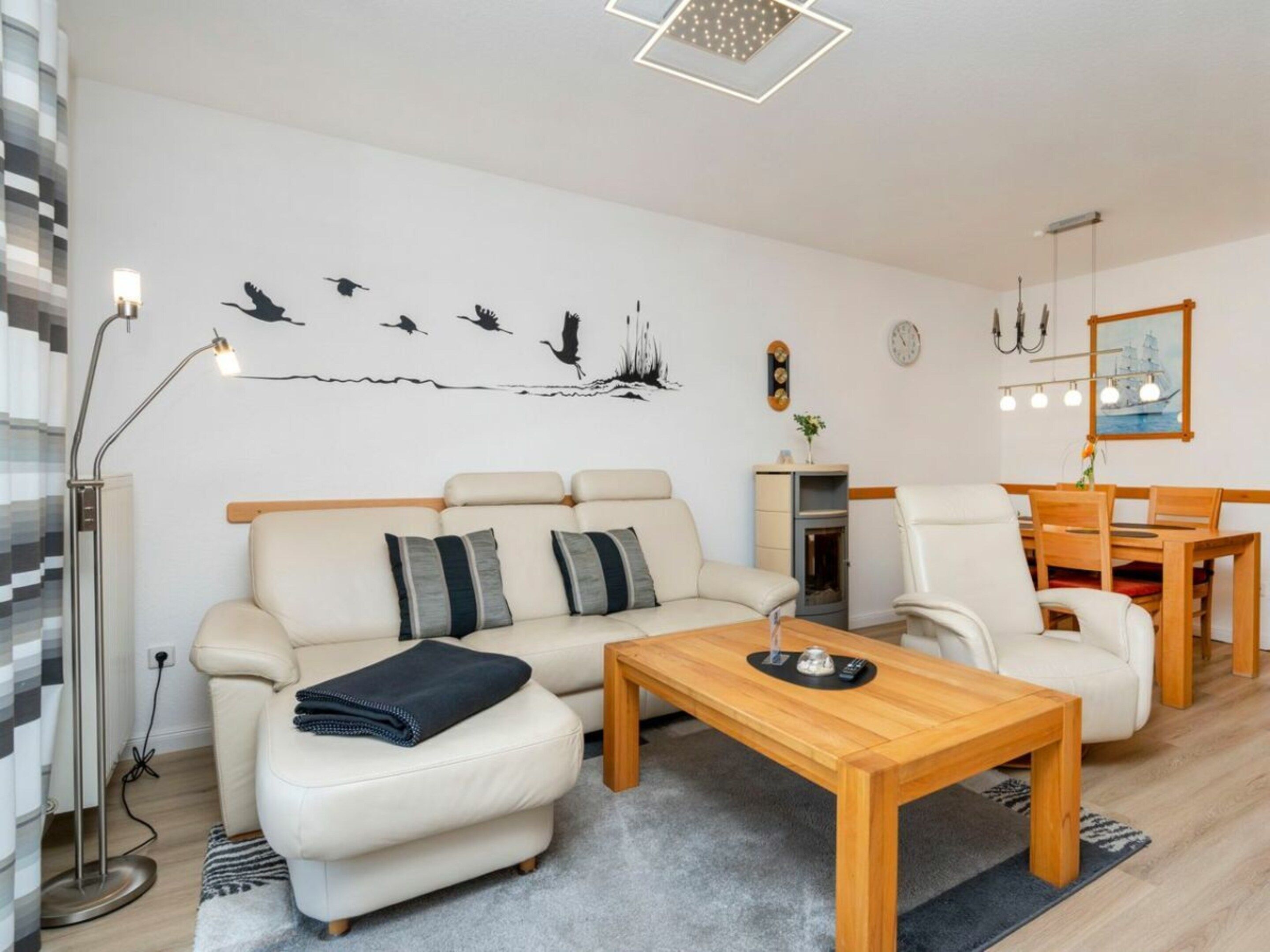 A modern living room with a sofa, armchairs, a coffee table, and a dining area.