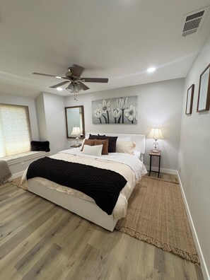 A bedroom with a bed, a ceiling fan, a painting, a lamp, and a window with blinds. - Spacious 5-bedroom house and Casita with endless views of the Temecula Valley (Temecula)