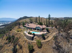 A large house with a swimming pool, surrounded by hills and sparse vegetation. - Spacious 5-bedroom house and Casita with endless views of the Temecula Valley (Temecula)