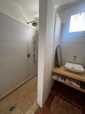 Un bagno con doccia, lavandino e finestra.