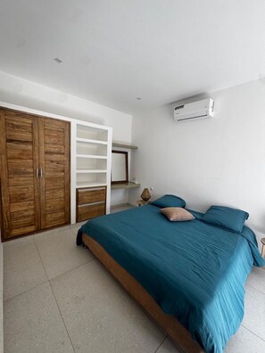 Una camera da letto con un letto, un armadio, una scaffalatura e un condizionatore d'aria.