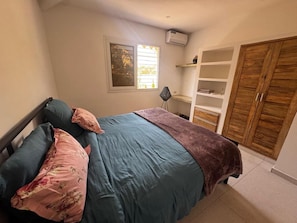 Una camera da letto con un letto, una finestra, un armadio e una scaffalatura.