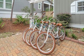 Une rangée de vélos avec des selles marron et des cadres blancs, garés sur un chemin pavé de briques.