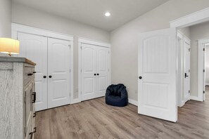 Un couloir avec des portes blanches, un meuble en bois et un fauteuil en forme de sac à haricots.