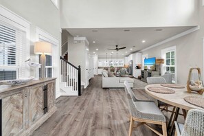 A spacious living area with a dining table, sofas, and a kitchen in the background. - Come & Sea by Stay on 30a (Inlet Beach)