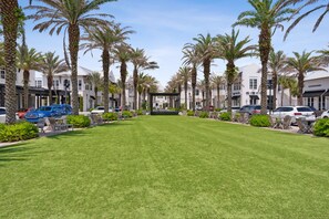 A well-maintained lawn with palm trees, a covered seating area, and a row of parked cars. - Come & Sea by Stay on 30a (Inlet Beach)
