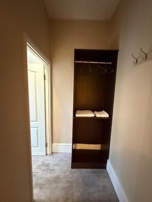 A narrow hallway with a closet containing shelves and hanging space.