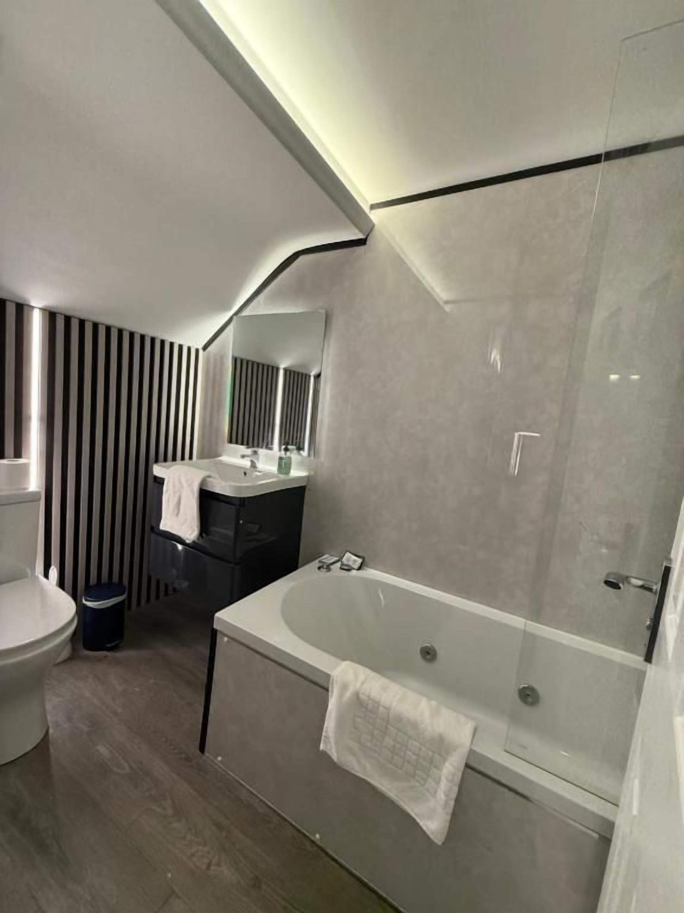 A modern bathroom with a bathtub, toilet, and vanity.