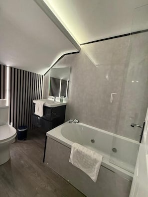 A modern bathroom with a bathtub, toilet, and vanity.