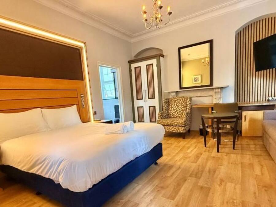 Een hotelkamer met een groot bed, een bureau, een stoel, een bank en een televisie.