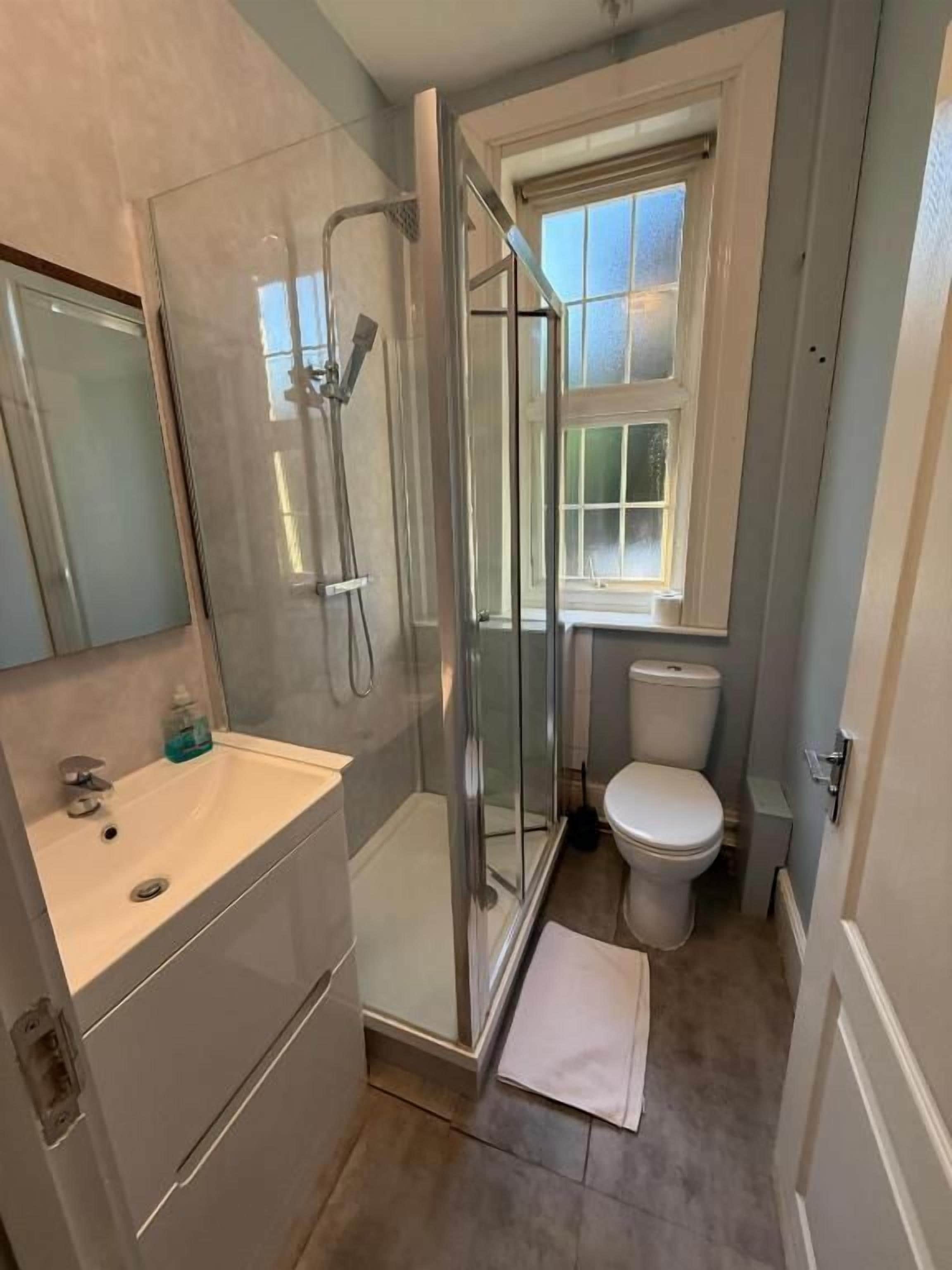 Un baño con cabina de ducha de vidrio, un inodoro y un lavabo.