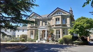 A large two-story house with a symmetrical facade, a central entrance with a portico, and a well-maintained garden.